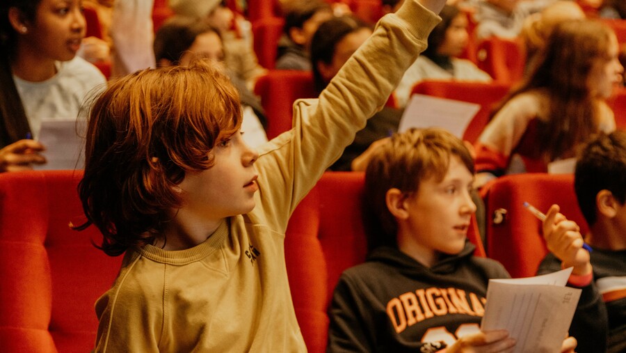 Kind met vinger in de lucht tijdens schoolvoorstelling 