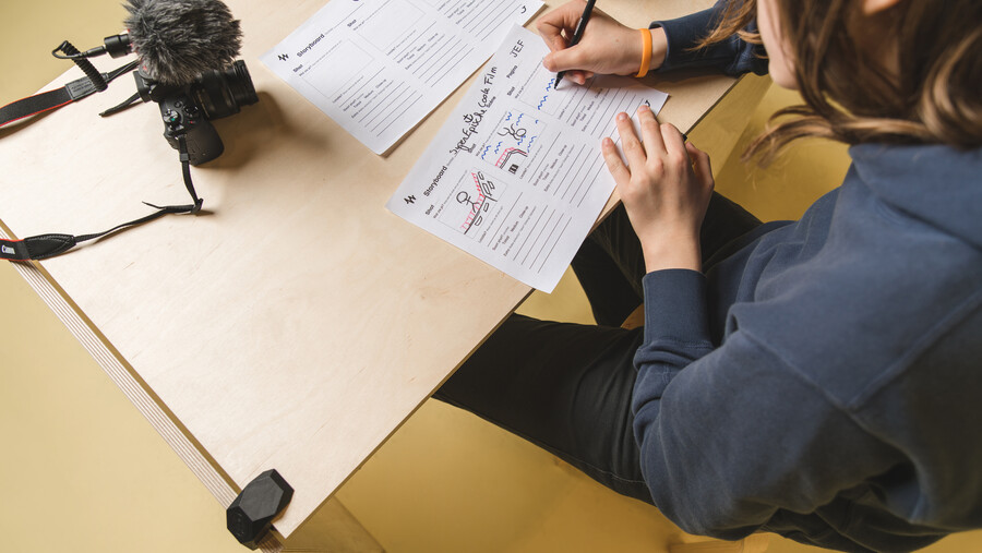 workshop kortfilm maken - jongere werkt aan storyboard met camera op de tafel